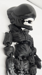 Side profile view of the flexible Xenomorph toy showing the elongated head, back tubing, and arm articulation joints