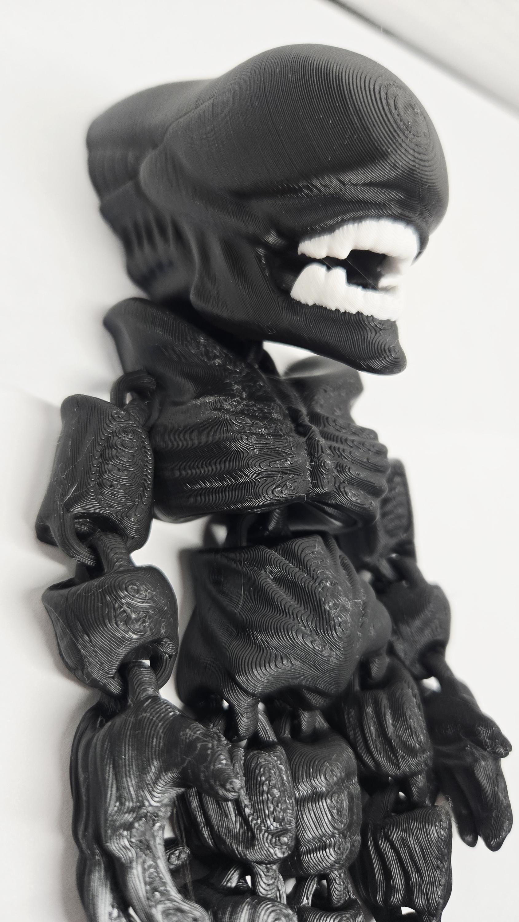 Side profile view of the flexible Xenomorph toy showing the elongated head, back tubing, and arm articulation joints